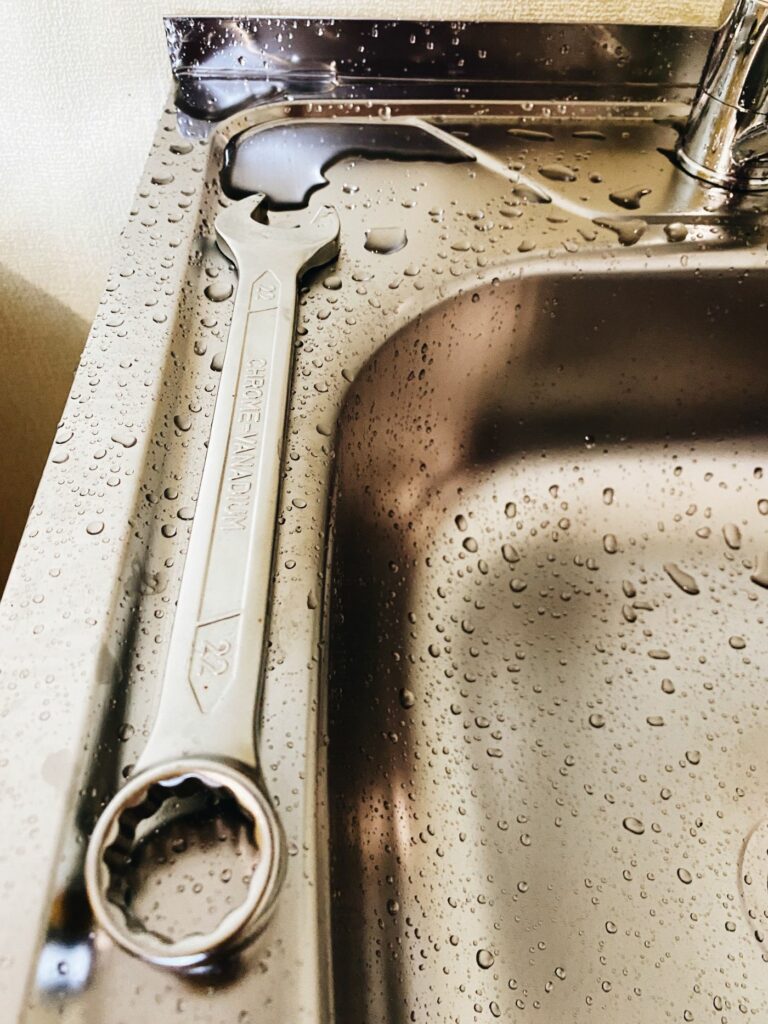 Clé de maintenance posée près d’un évier avec gouttes d’eau