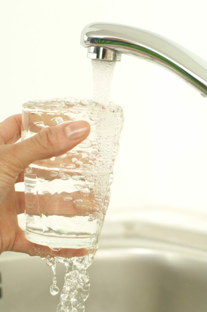 Verre rempli d’eau claire sous un robinet