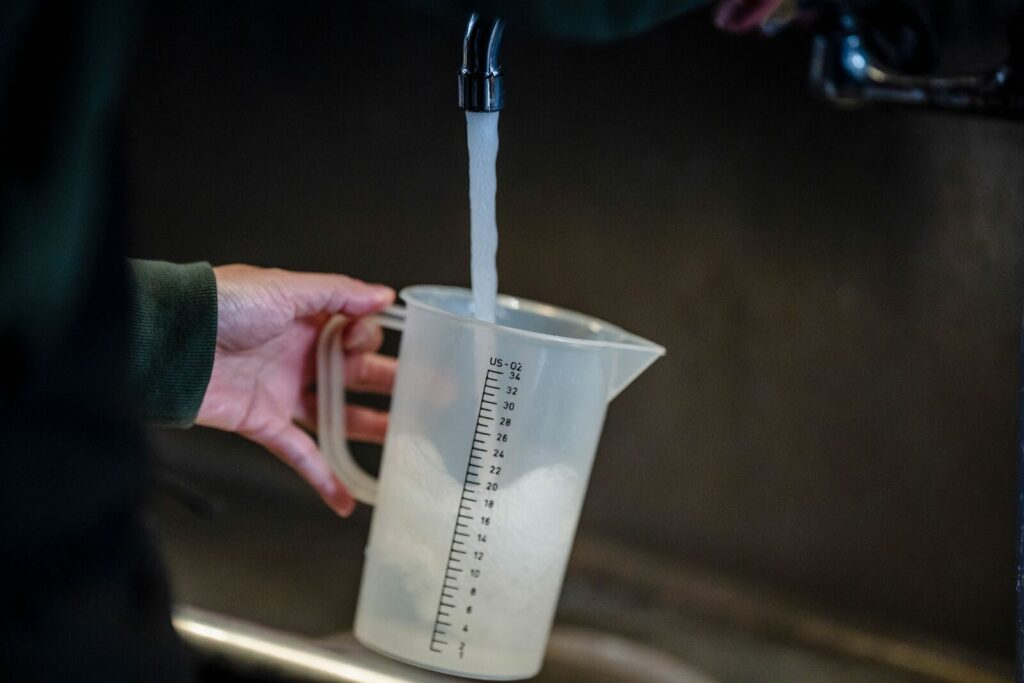 Pichet gradué rempli d’eau sous un robinet